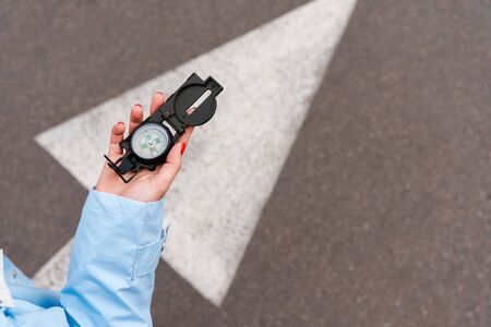 cropped view of woman holding vintage compass near road