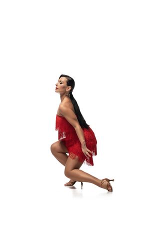 elegant dancer squatting with closed eyes while performing tango on white backgroundの写真素材