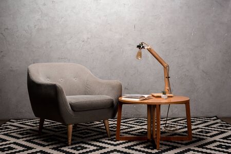 interior of living room with comfortable grey modern armchair near wooden table and lamp on carpetの写真素材