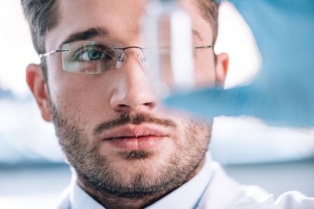 close up of handsome bearded immunologist holding bottle in clinic