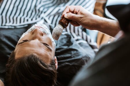 top view of barber applying shaving cream on face of manの写真素材