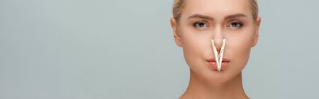 panoramic shot of attractive woman with wooden pin on nose isolated on grey