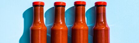 Top view of bottles with tomato sauce on blue background, panoramic shotの写真素材