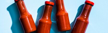 Top view of bottles with tasty tomato sauce on blue background, panoramic shotの写真素材