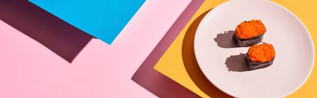 fresh nigiri with red caviar on blue, pink, orange background, panoramic shotの写真素材