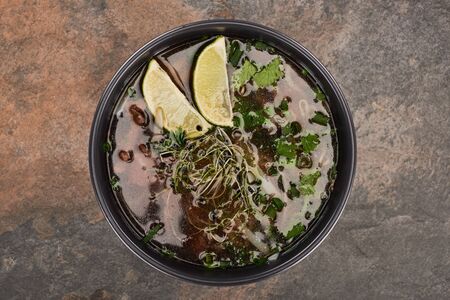 top view of pho in bowl with lime and coriander on stone backgroundの写真素材