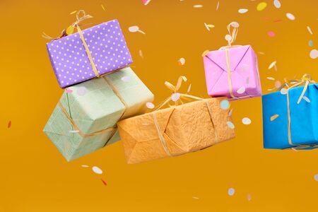falling confetti near colorful presents on orange 