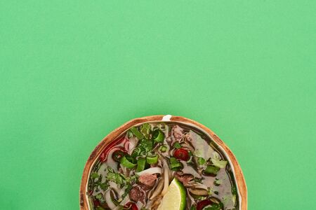 top view of pho in bowl on green background