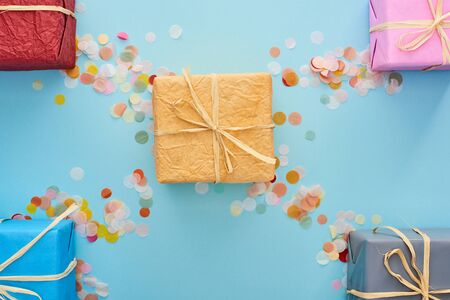 top view of wrapped presents near colorful confetti on blue