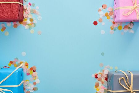 top view of wrapped presents near colorful confetti on blueの写真素材