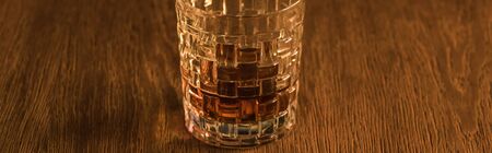 Panoramic shot of brandy in textured glass on wooden table