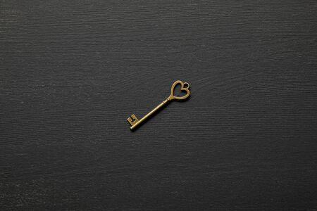 top view of vintage rusty key with heart on black background