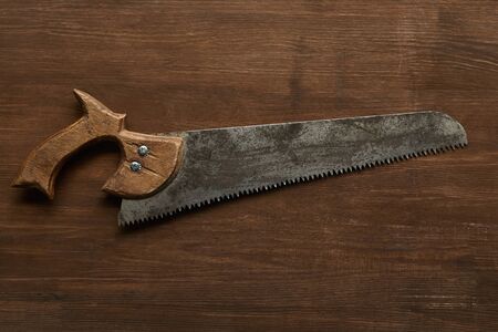 top view of old rusty saw on wooden table