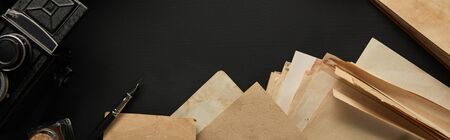 top view of vintage camera, paper, fountain pen on black background, panoramic shotの写真素材