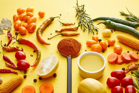 Ripe vegetables with olive oil and spices on yellow backgroundの写真素材