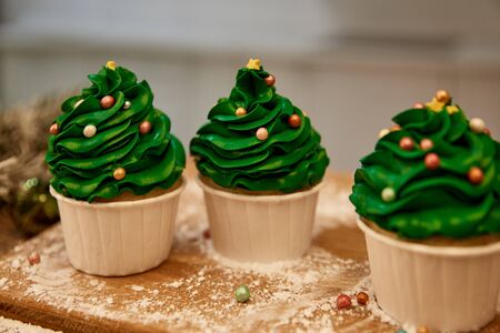 Decorated cupcakes with green cream and sugar sprinkles on cutting board with flour