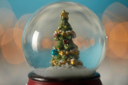 close up of snowball with christmas tree standing on blue in snow with spruce branches and lights bokehの写真素材