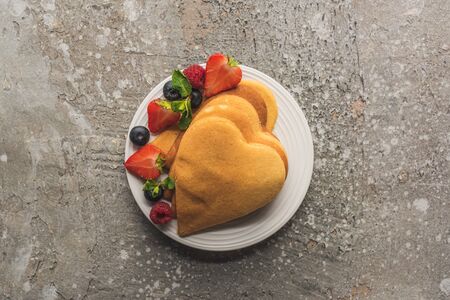 top view of heart shaped pancakes with berries on grey concrete surfaceの写真素材