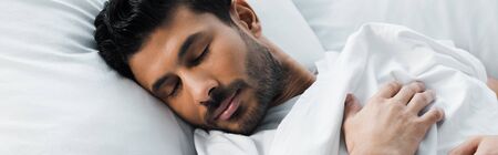 panoramic shot of handsome bi-racial man sleeping in bed in morning