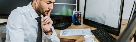 panoramic shot of pensive bi-racial trader looking down in office