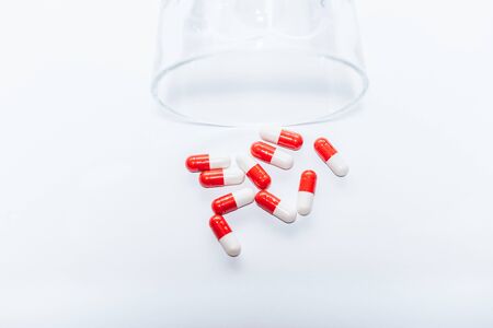 red and white capsules near overturned glass on white background, suicide prevention conceptの写真素材
