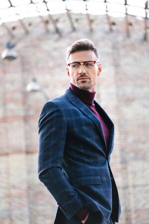 Side view of handsome businessman looking away on urban streetの写真素材