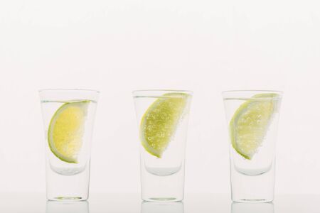 fresh tequila with lime in row isolated on white