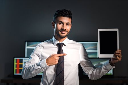 smiling bi-racial trader pointing with finger at digital tabletの写真素材