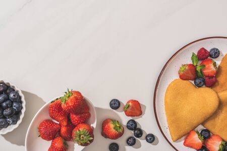 top view of tasty heart shaped pancakes with berries and mint on white backgroundの写真素材