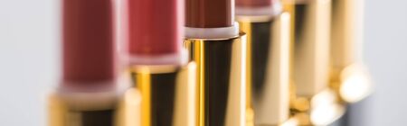 close up view of assorted lipsticks in luxury tubes in line isolated on white background, panoramic shotの写真素材