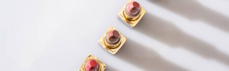 top view of assorted lipsticks in luxury tubes in line on white background, panoramic shotの写真素材