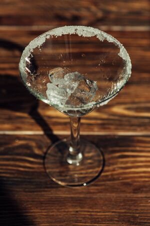 martini glass with ice decorated with sugar on wooden surface in sunlightの写真素材