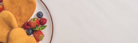 top view of tasty heart shaped pancakes with berries and mint on white background, panoramic shotの写真素材