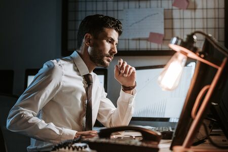side view of handsome bi-racial trader using computer and sitting at tableの写真素材