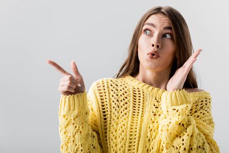 surprised girl pointing with finger while looking away isolated on greyの写真素材