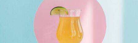 fresh yellow lemonade with lime in pink circle on blue background in sunlight, panoramic shotの写真素材