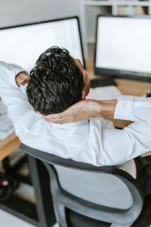 high angle view of bi-racial trader with crossed arms sitting at tableの写真素材
