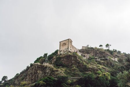 SAVOCA, ITALY - OCTOBER 3, 2019:  low angle view of church of san nicolo on hill near green trees against sky with cloudsのeditorial素材