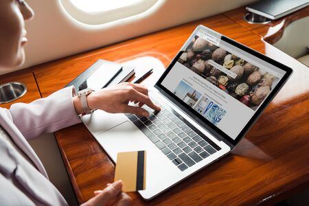 cropped view of businesswoman using laptop with depositphotos website while shopping online in private planeのeditorial素材