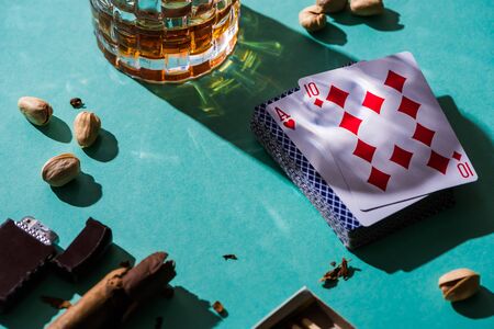 KYIV, UKRAINE - NOVEMBER 7, 2019: Glass of brandy with pistachios, playing cards and cigar on green backgroundのeditorial素材