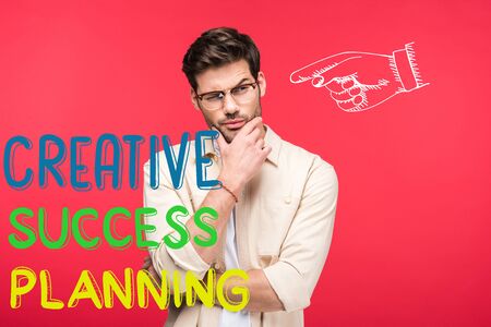 pensive man in glasses touching chin isolated on red with creative, success and planning illustrationの写真素材