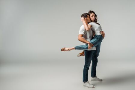 dancers in t-shirts and jeans dancing bachata on grey background