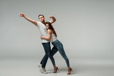 dancers in denim jeans dancing bachata on grey backgroundの写真素材