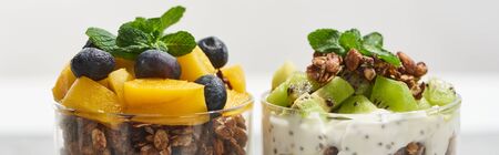 close up view of fresh granola with kiwi and canned peach with blueberries isolated on white, panoramic shotの写真素材
