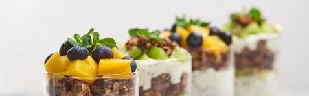 selective focus of fresh granola with kiwi and canned peach with blueberries isolated on white, panoramic shotの写真素材