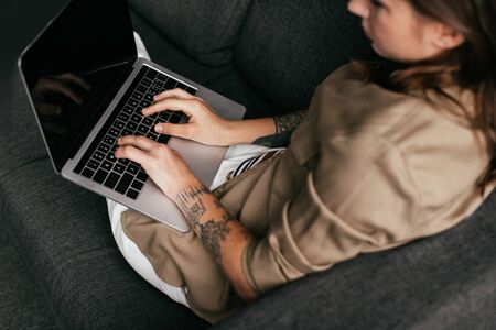 Overhead view of woman using laptop with blank screen on sofa, selective focusの写真素材