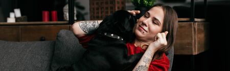 Panoramic shot of beautiful girl playing with pug dog on sofa