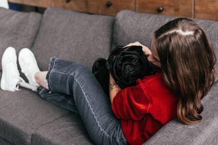 Selective focus of girl with leg prosthesis stroking pug on sofaの写真素材