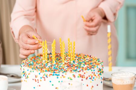 cropped view of senior woman putting candles in delicious birthday cakeの写真素材
