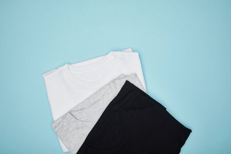 top view of blank basic black, white and grey t-shirts isolated on blueの写真素材